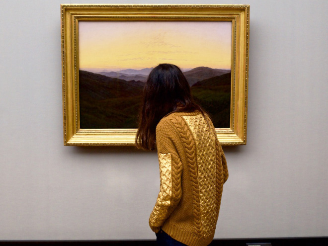 Painting's frame perfectly matching museum visitor's sweater.