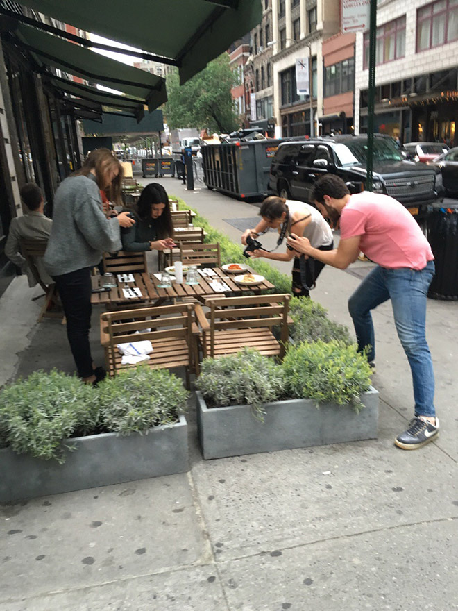 A picture of hipsters taking a picture of food.