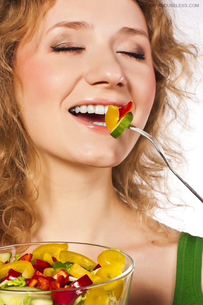 Woman laughing alone with salad.